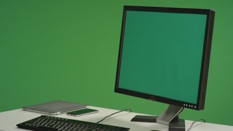 desk with computer monitor on green screen