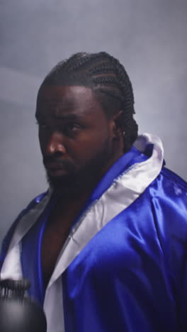 Vertical-Video-Of-Male-Boxer-Wearing-Gloves-And-Robe-Standing-In-Ring-For-Boxing-Match-Sparring-And-Warming-Up-Before-Fight