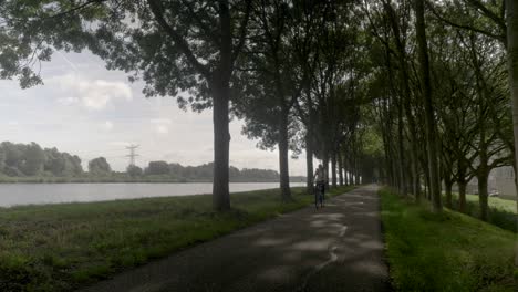 mujer en bicicleta por la carretera en un típico campo de pueblo holandés