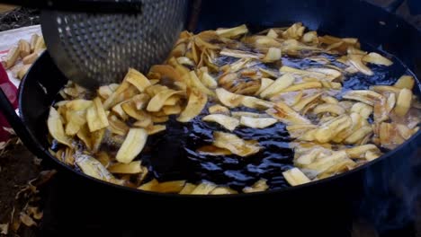 plátanos fritos en rodajas con aceite caliente en una sartén sobre comida callejera, chips de plátano fritos en la sartén con aceite hirviendo, plátanos fritos en una sartén con aceite hirviendo