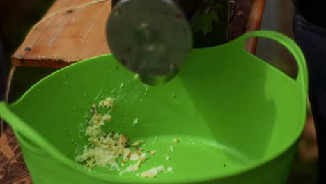 older man grinding apples with an electric grater into a green bucket