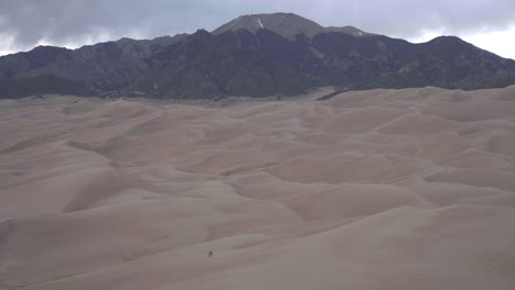 人們穿過荒涼的沙丘田地,背後是山