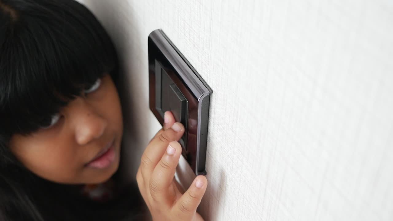 A young girl is looking at a light switch