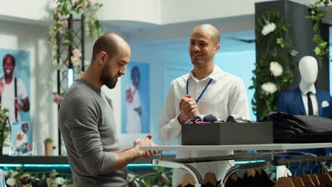 cliente interactuando con un asociado de ventas en una tienda de ropa para hombres