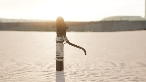 Rusty-old-metal-water-pump-on-sand-beach