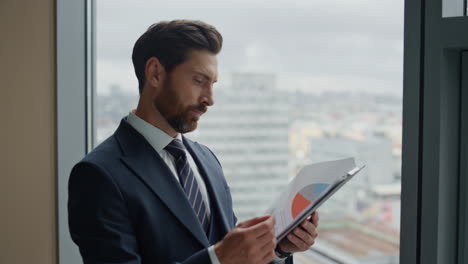 Business-man-reading-documents-with-pie-chart-analyzing-company-work-close-up