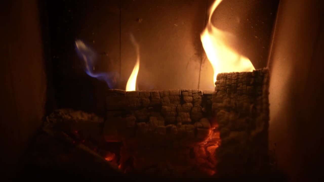 Glowing embers and burning wood in a fireplace with warm flickering flames