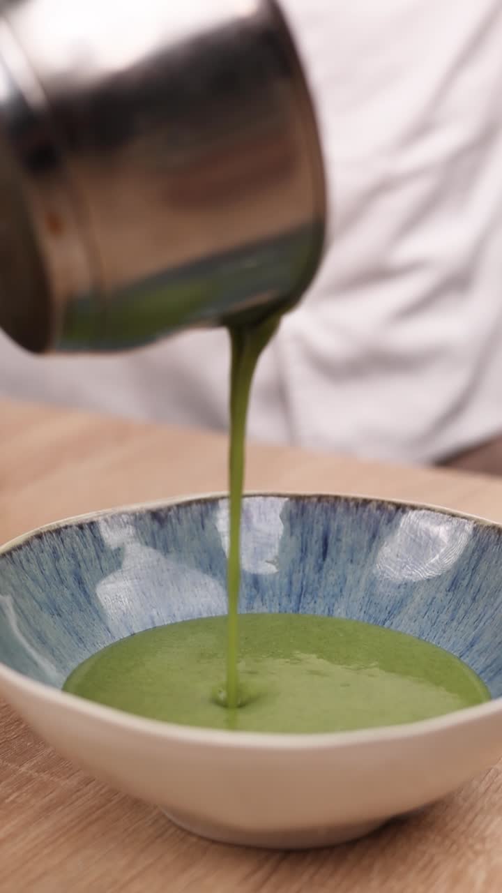 chef vertiendo sopa verde en un cuenco