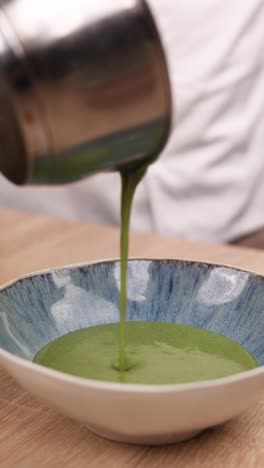 chef pouring green soup into a bowl