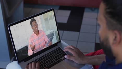 hombre de oriente medio teniendo una videollamada con un colega de oficina masculino en una computadora portátil