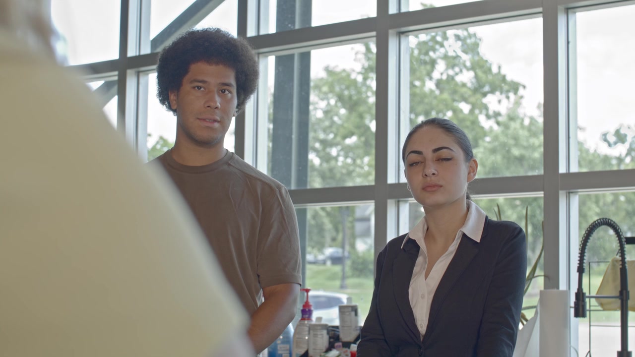 Three workers in their 20's talking in an office setting with stable over the shoulder video.