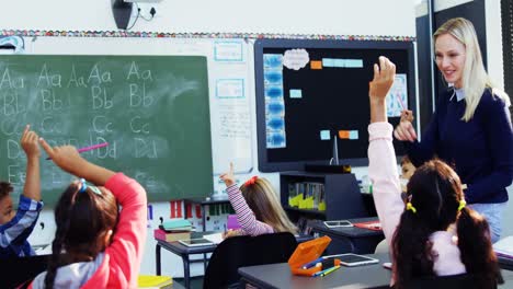 teacher asking questions to her students in classroom