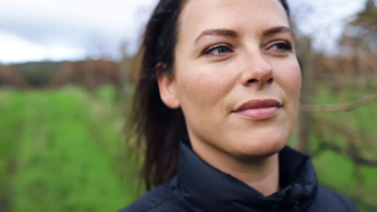 una joven atractiva camina por un viñedo de invierno, luciendo contenta