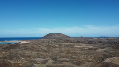 aerial drone footage flying over the rugged terrain of the island of wolves, spain under a beautiful clear blue sky