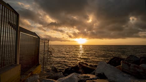 Goldene-Wellen-Bewegen-Sich-Im-Zeitraffer-Des-Sonnenaufgangs-Im-Hafen-Von-Mitilini---Mytilene-Auf-Lesbos,-Griechenland-Mit-Wunderschönen-Wolken,-Die-über-Das-ägäische-Meer-Im-Mittelmeer-Blicken-Und-Die-Türkische-Küste-überblicken