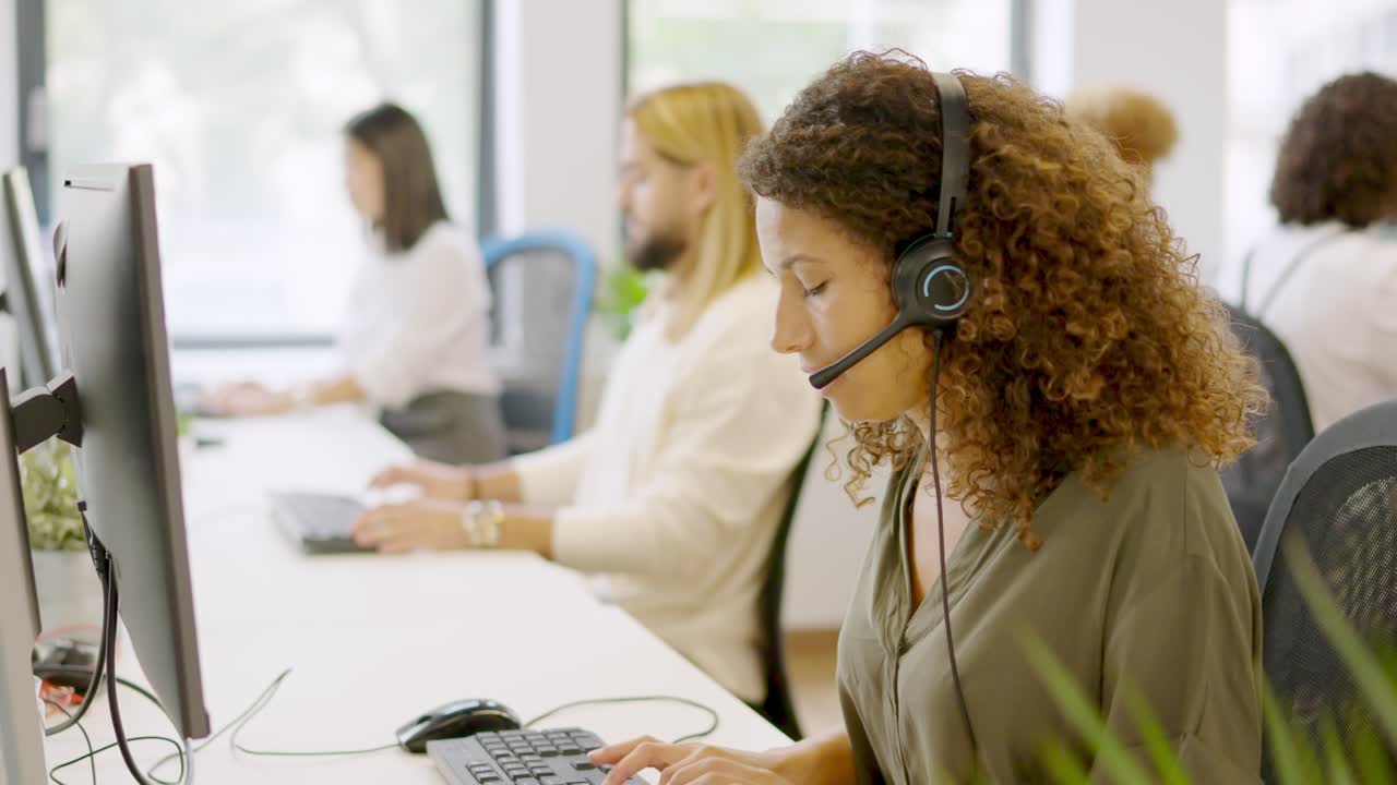 Concentrated woman using computer and headset in a coworking