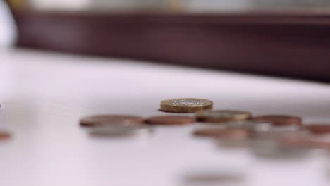 solo british pound coin spinning and falling in slow motion with other coins lying flat