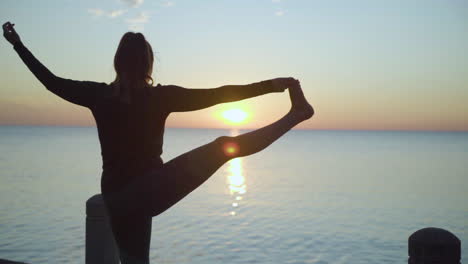 woman extending leg into standing yoga pose at sunrise. slow motion.