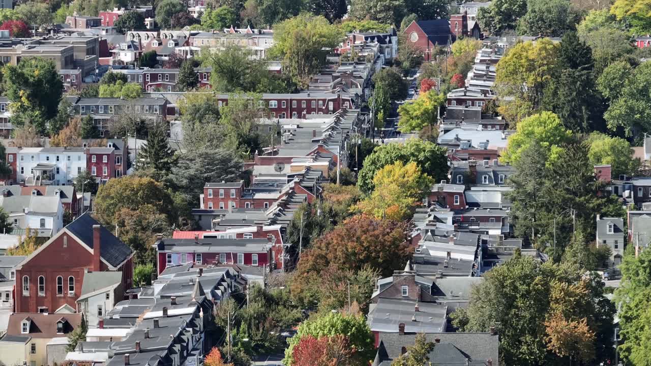 Row of historic houses and homes along tree-lined street in american town. Aerial wide shot. Sunny autumnal day in USA. Roofs of classical and colonial houses with chimney