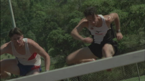 two athletes compete running and jumping hurdles