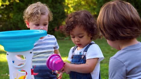 Group-Of-Young-Children-Playing-With-Water-Table-In-Garden