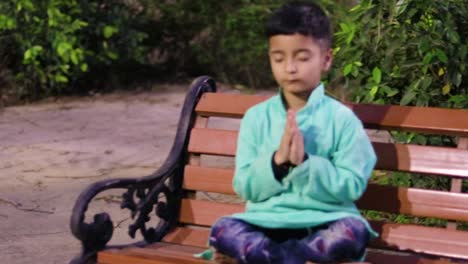 young kid meditating at wood bench in traditional dress at evening from different angles