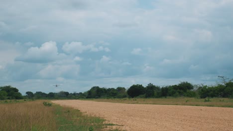 Small-aeroplane-approaching-and-landing-on-gravel-landing-strip-in-tropical-Africa-Zanzibar-on-cloudy-day