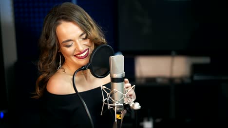 una chica hermosa canta en un micrófono en un estudio de grabación