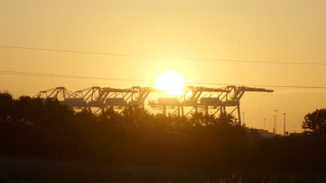 toma estática de las brillantes vistas del cielo del amanecer sobre las grúas del puerto de envío industrial