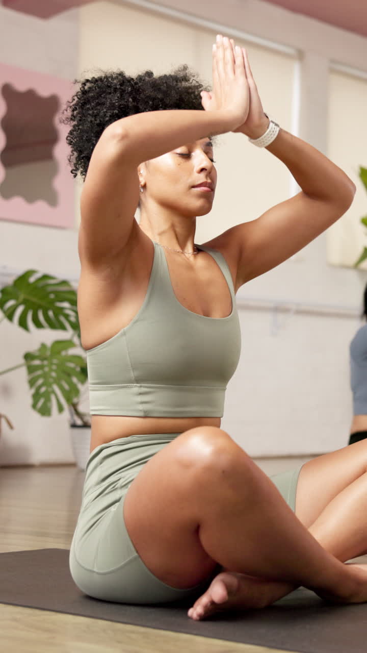 Donna calma che medita nella posizione del loto durante una lezione di yoga