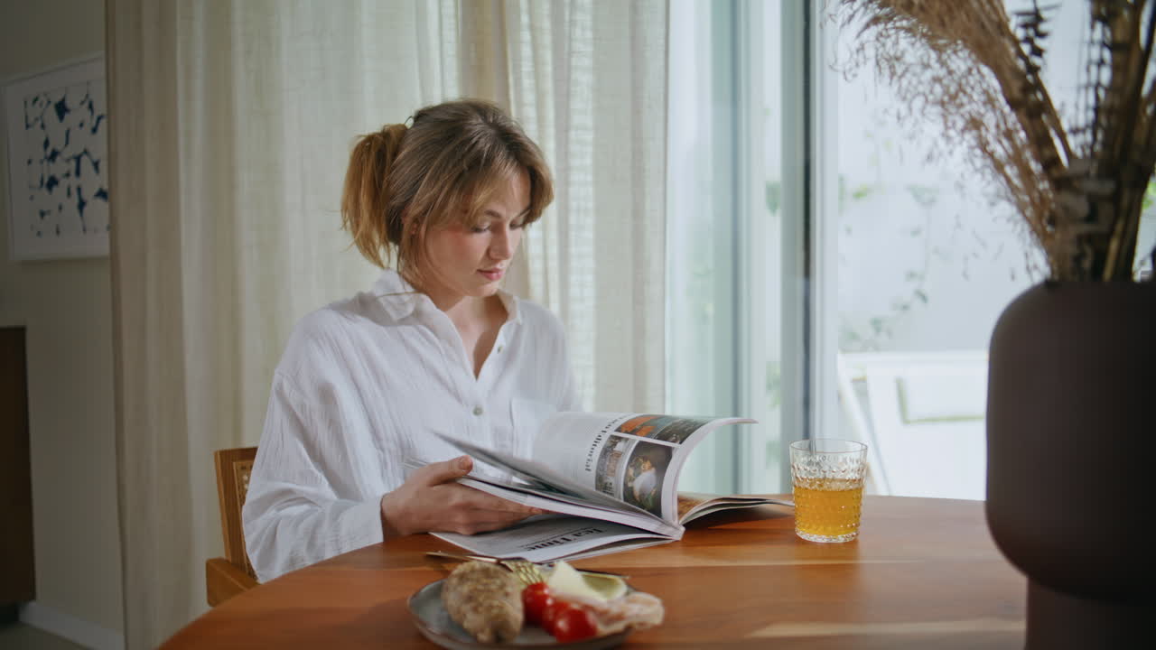 Morning woman reading magazine at apartment table closeup. Lady flipping pages