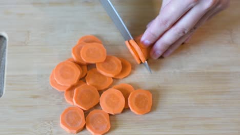 close-up of woman's hand cutting a carrot.top view