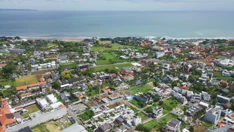 Aerial-view-of-Berawa,-Canggu,-Bali-with-villa,-beach-clubs-and-real-estate-construction-sites-next-to-Berawa-beach