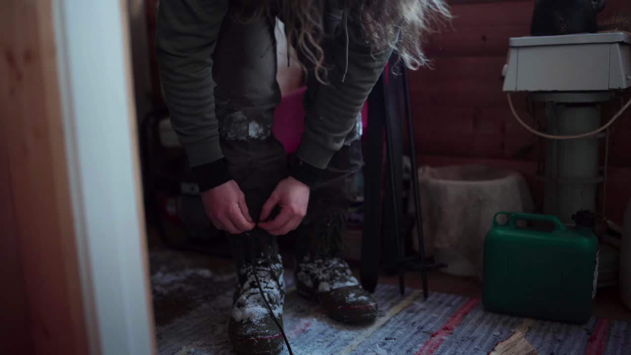 L'uomo sta allentando i lacci delle sue scarpe, coperte di neve durante l'inverno a Bessaker, contea di Trondelag, Norvegia - Primo piano.