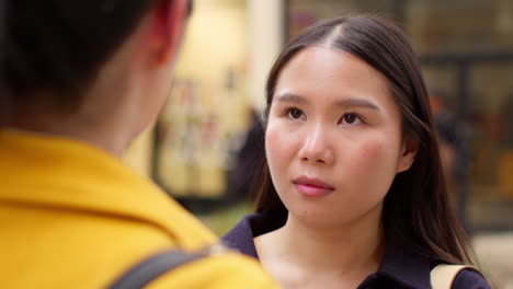 close up of two smiling young female friends meeting and talking in urban setting together 2