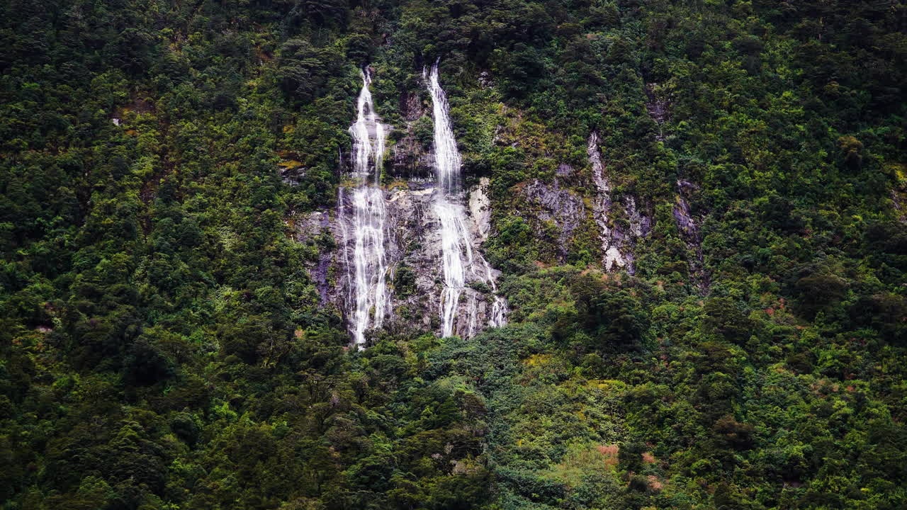 cascada que cae en cascada por un acantilado rocoso alto en nueva zelanda, vista aérea de drones