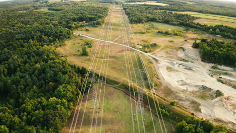 aerial drone view of high voltage transmission power lines passing through forest in rural countryside