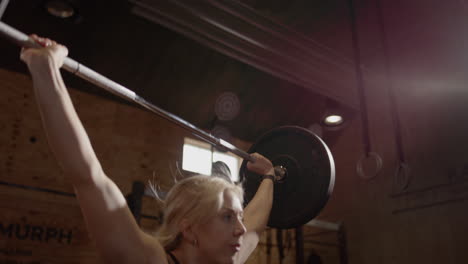 slomo of blonde woman showing good form during snatch weightlifting move in gym