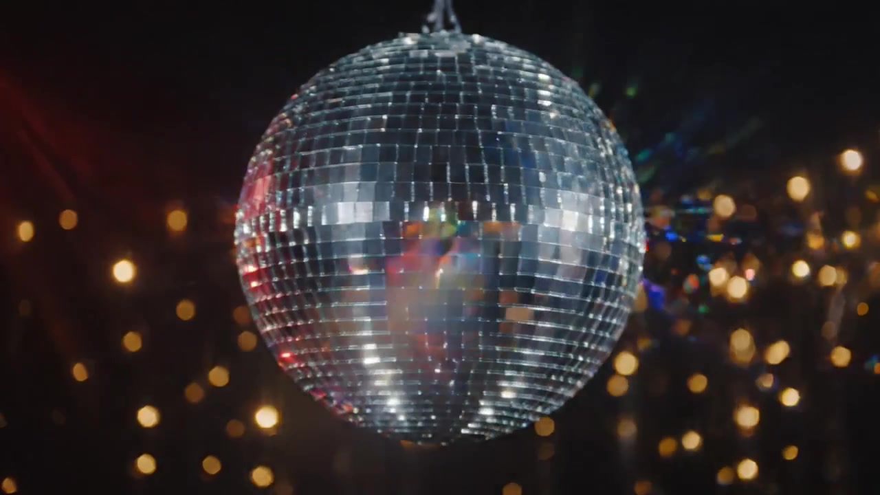 Uno spettacolo dinamico di luce e riflessi: una scintillante palla da discoteca cattura la scena con raggi colorati e una brillante effervescenza.