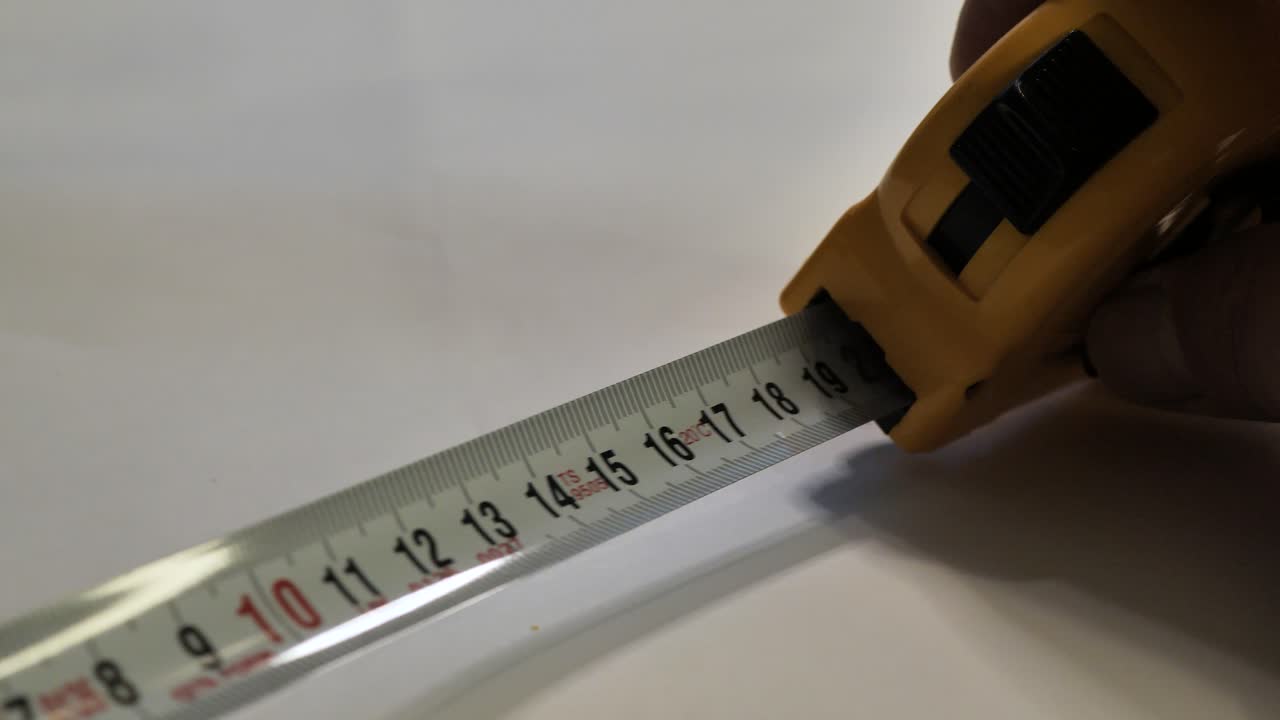 Tape measure. Hands pull the measuring yellow tape out. Roll of measuring tape. Scene B.