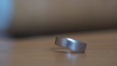 close up shot of wedding ring spinning in slow motion on wooden surface, shallow depth of field