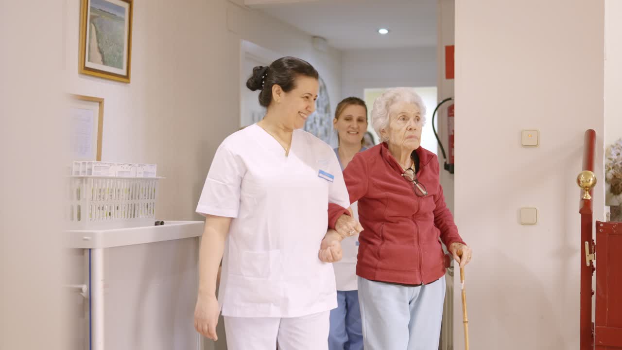 Caregivers holding arm of seniors while walking in a geriatric