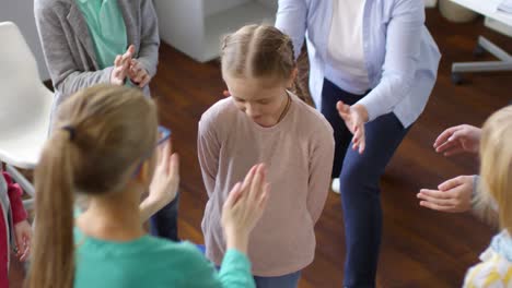 niña joven jugando al juego de la confianza en círculo con amigos y maestra