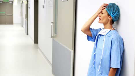 sad surgeon leaning on wall in corridor