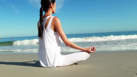 woman performing yoga at beach