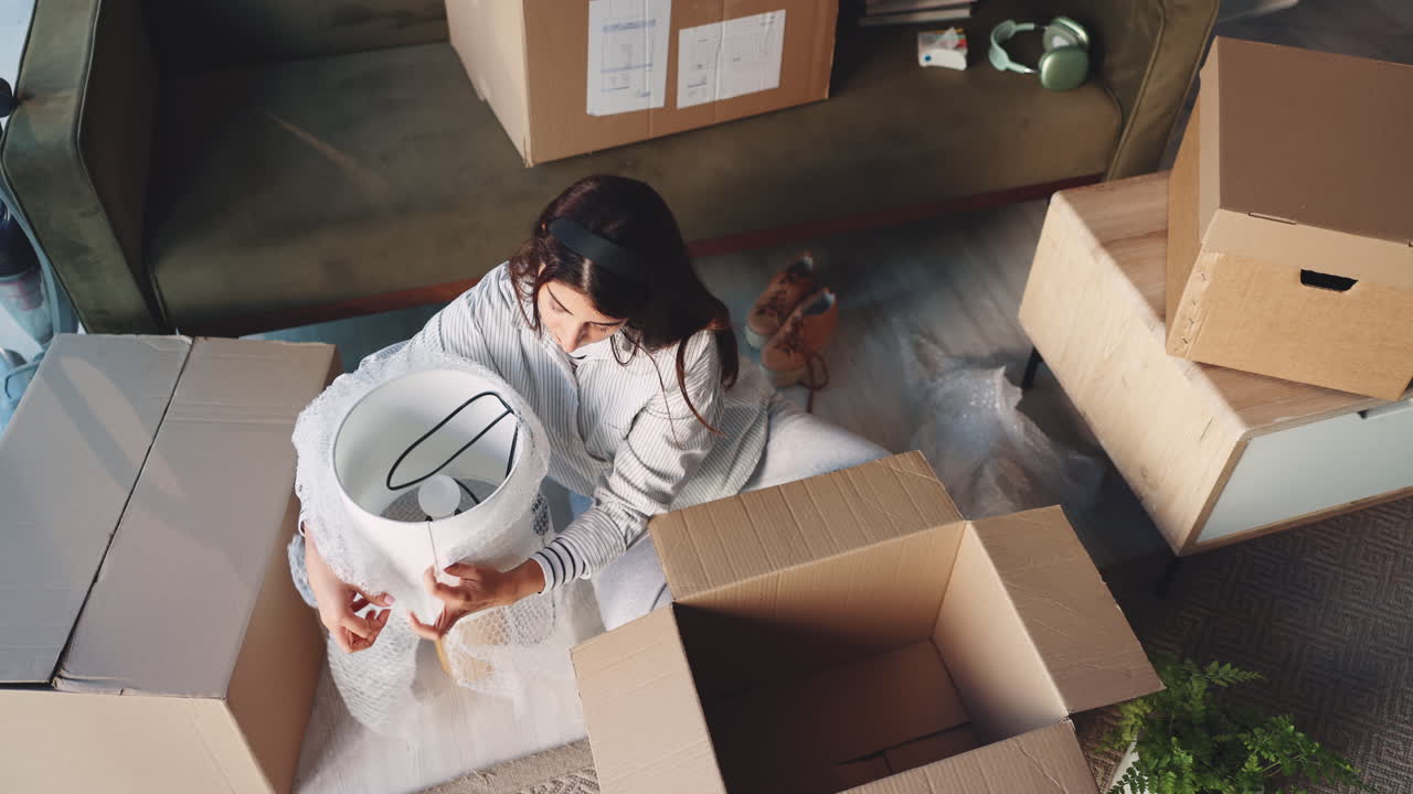 Woman packing lamp in a moving box