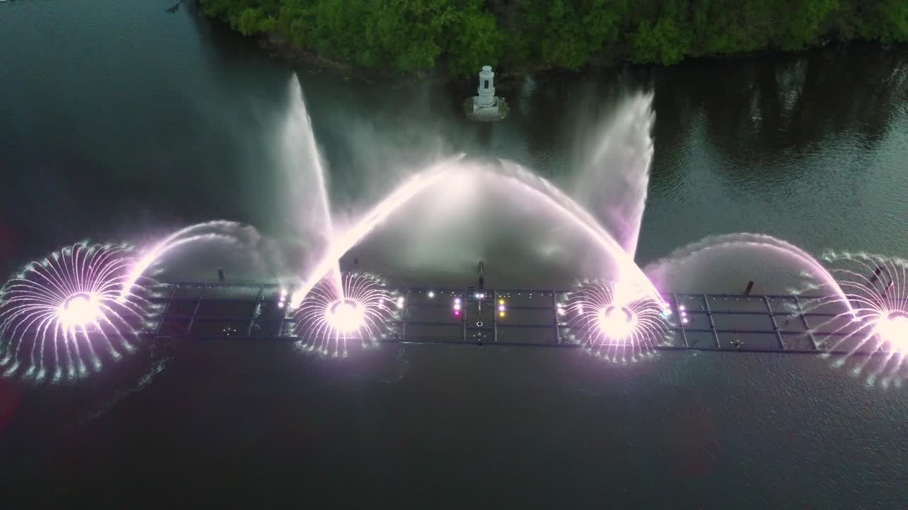 Water Music Fountain In Night. Aerial shot of the dancing colorful fountain with reflection on water at night