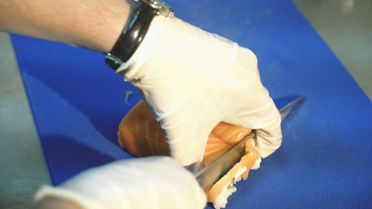 Professional sushi chef cutting rolls. Redfish. Sushi philadelphia