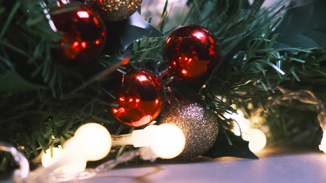 fondo de año nuevo o navidad. primer plano de la rama de abeto artificial decorada con bolas de navidad rojas y doradas y bombillas de guirnaldas intermitentes