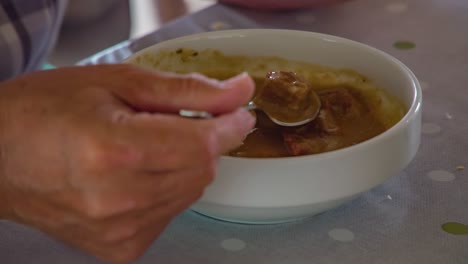mano trayendo goulash de comida a la boca. tiro estático